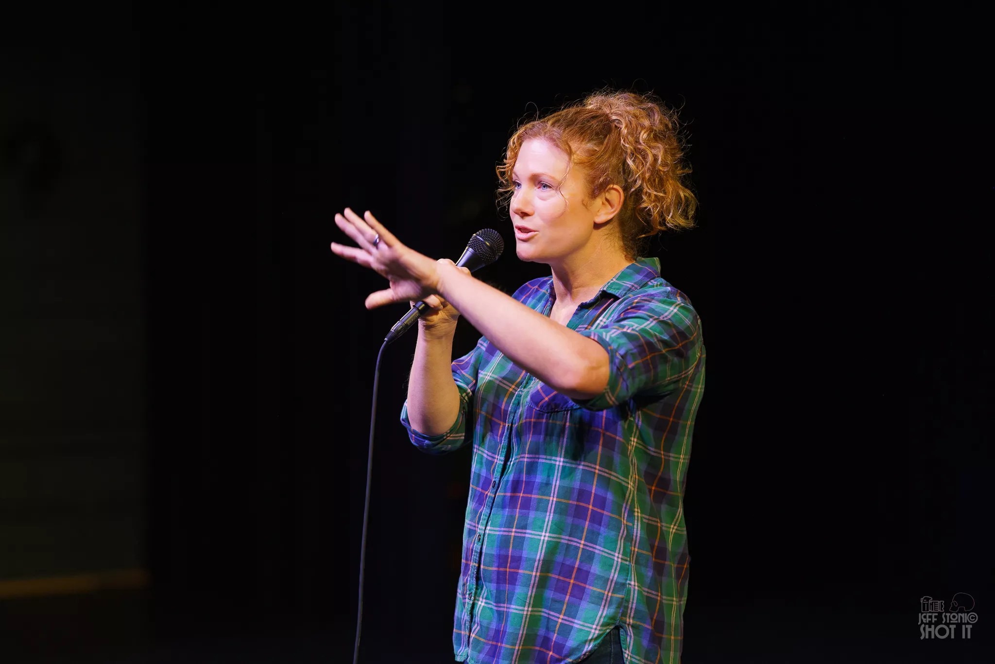 A comedian speaks into a microphone onstage.