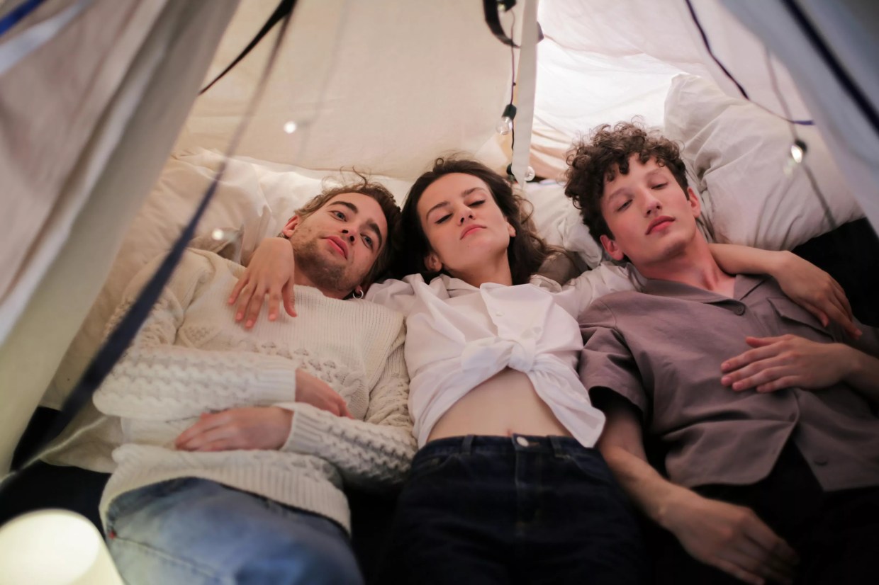 Three people cuddle in bed