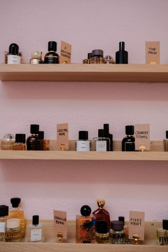 A pink wall with shelves of perfume bottles