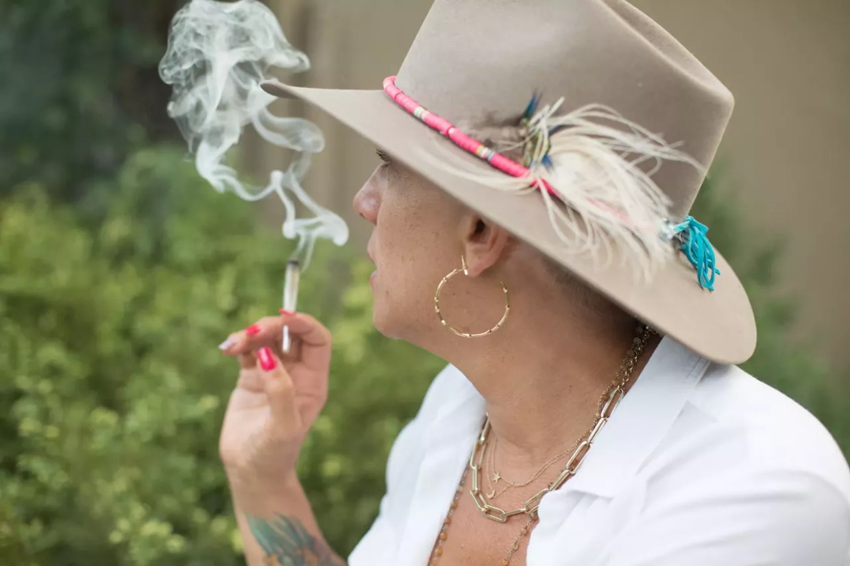 woman in hat smokes joint
