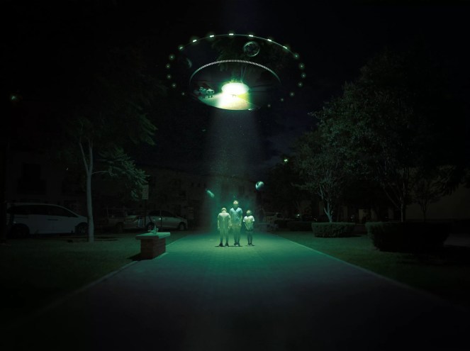 Aliens stand under a green light