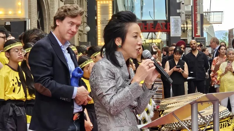 woman talking into mic in front of man
